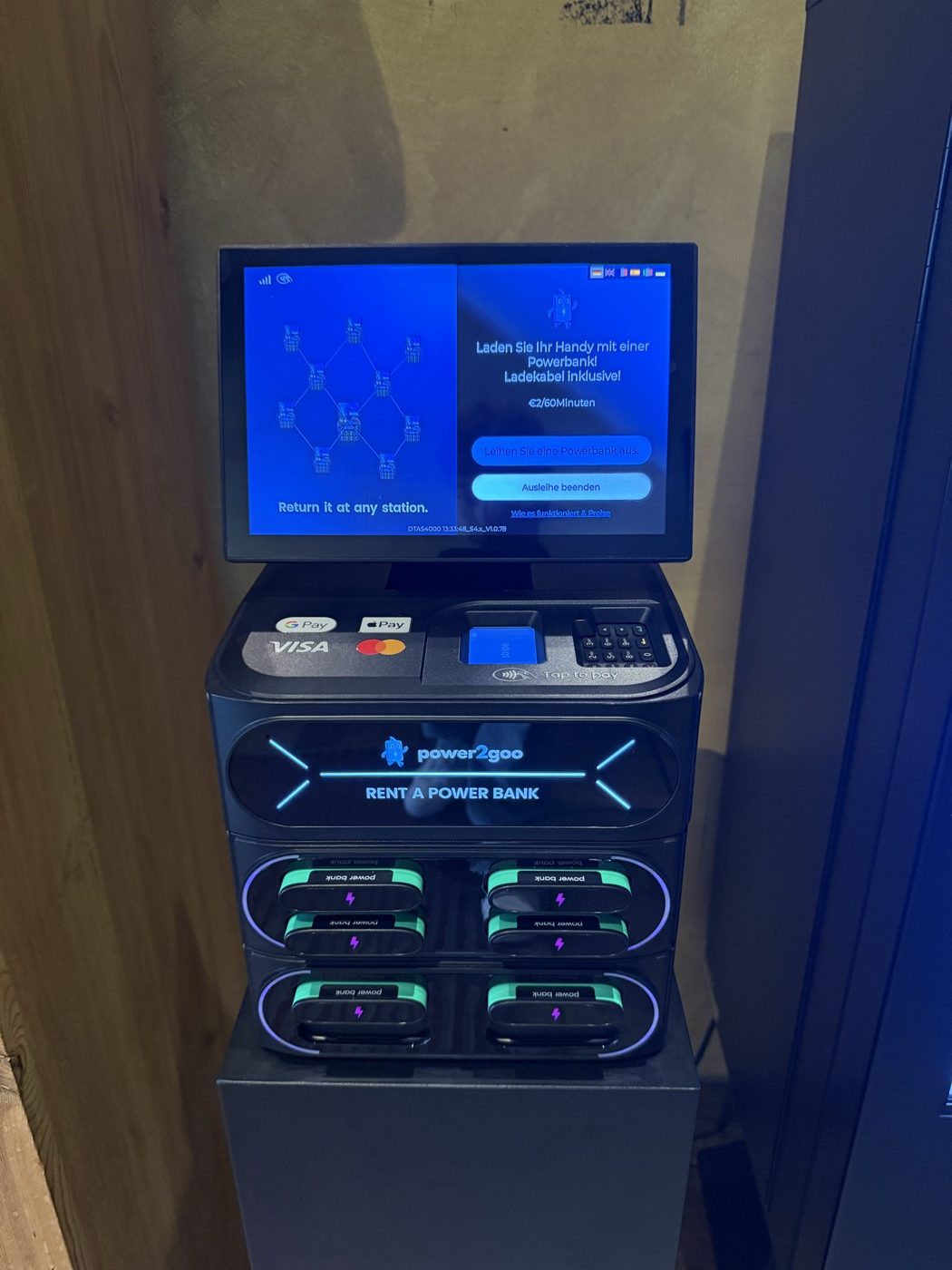 Nahaufnahme einer power2goo Powerbank-Station mit Kartenleser für Visa, Mastercard, Apple Pay und Google Pay sowie eingesteckten Powerbanks